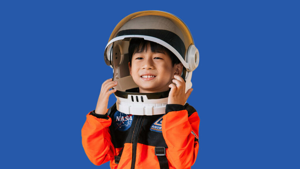 A young boy wears a NASA astronaut costume with a helmet