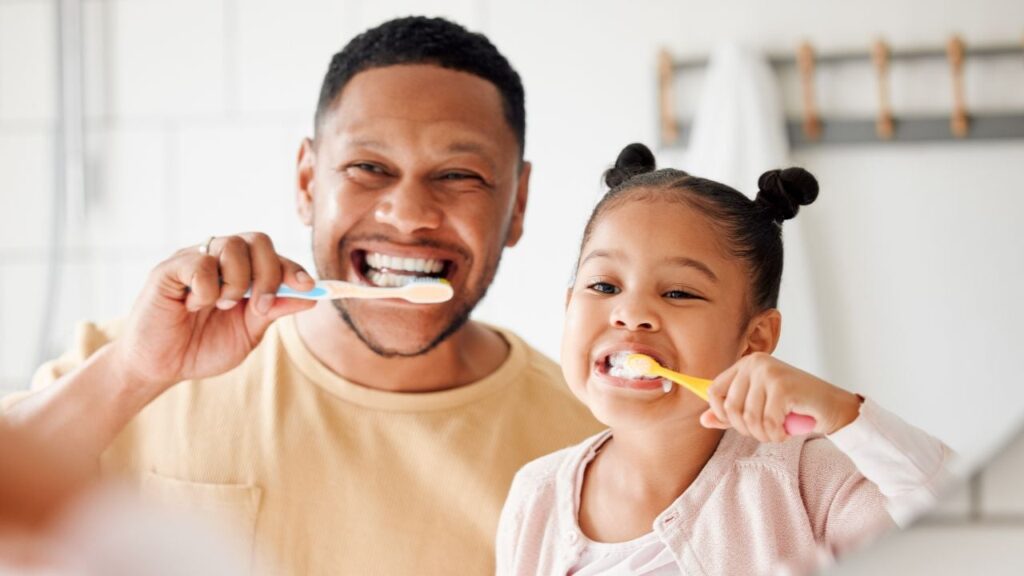 A father and daughter brush their teeth together